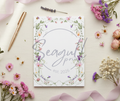 An elegant A6 floral notepad sitting on a desk alongside a gold pen, showcasing its stylish design for stationery enthusiasts.